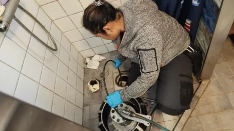 Rörmokare från Allmänna Rörjouren rensar en golvbrunn med rensmaskin